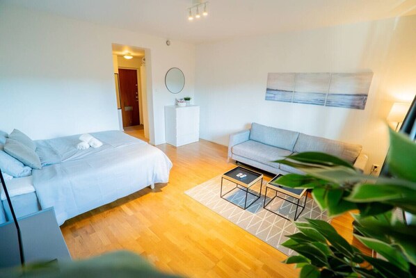 Ein modernes Schlafzimmer mit einem Bett, einer grauen Couch, einem kleinen Tisch und einem Spiegel.