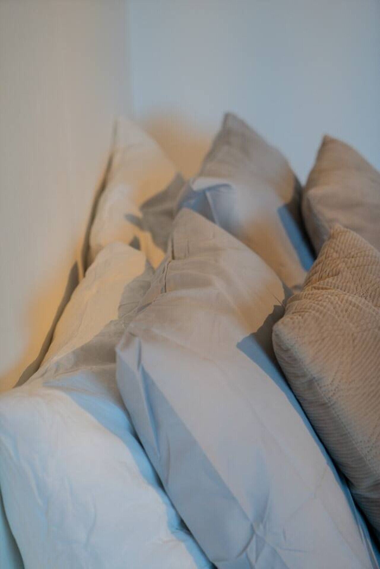 A bed with multiple pillows and a textured blanket.