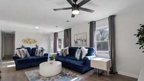 A modern living room with two sofas, a round coffee table, a side table, and a ceiling fan.