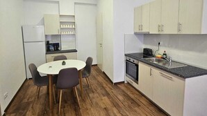 A compact kitchen with a dining table, chairs, a refrigerator, a stove, and cabinets.