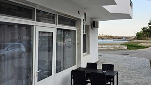 A building with a white exterior, large windows, a stone-paved patio, and a view of the sea.