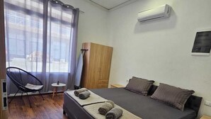 A bedroom with a bed, a chair, a small table, and a wardrobe.