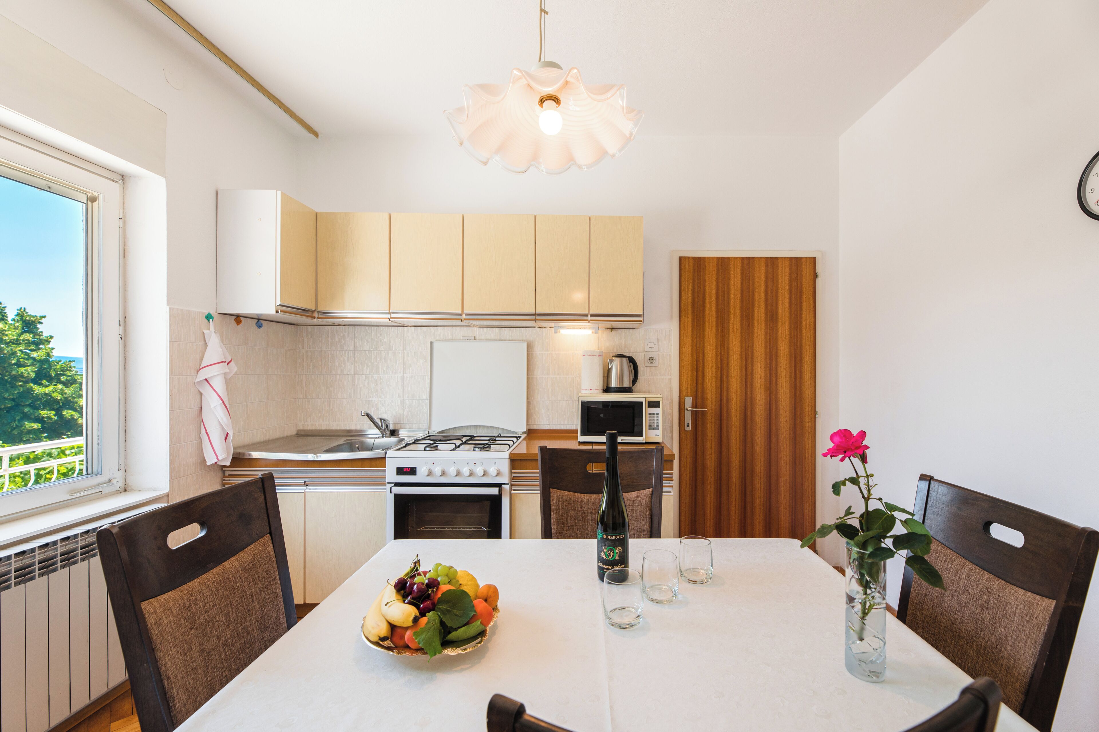 A modern kitchen with white cabinets, a stove, and a dining table with chairs.