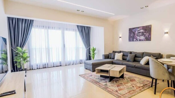 A modern living room with a sofa, coffee table, and dining area. - Luxury 2BR • Porto New Cairo • Pool & 3 Baths (New Cairo 1)