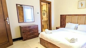 A bedroom with a wooden bed, a nightstand, a wooden dresser, a mirror, and a door.