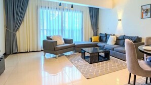 A modern living room with a sectional sofa, a small sofa, a coffee table, and a dining area with a table and chairs.