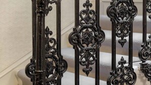 A staircase with ornate black metal railings and a wooden handrail. - Tummel Apartment (Edinburgh)