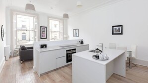 A modern kitchen with a central island, a built-in oven, and a large window providing natural light. - Tummel Apartment (Edinburgh)