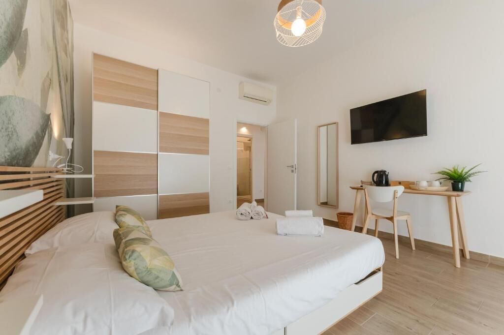 Ein modernes Hotelzimmer mit einem großen Bett, einem Schreibtisch mit Stuhl, einem Flachbildfernseher und einer Topfpflanze.