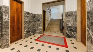 A hallway with marble walls, a wooden door, a red mat, and a staircase leading to another room. - Smart Arena Rooms - 10 minuti dall'Arena (Verona)
