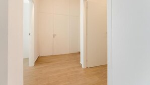 A hallway with white walls and wooden flooring, leading to a closed door. - Smart Arena Rooms - 10 minuti dall'Arena (Verona)