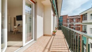 A balcony with a tiled floor, a dining area with a table and chairs, and a TV mounted on the wall. - Smart Arena Rooms - 10 minuti dall'Arena (Verona)