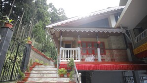 A staircase with potted plants leading to a building with a reception area. - Latitudee Boutique Rooms (Darjeeling)