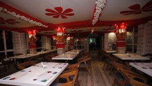 A restaurant with multiple tables and chairs, red and white decor, and traditional Chinese elements. - Latitudee Boutique Rooms (Darjeeling)