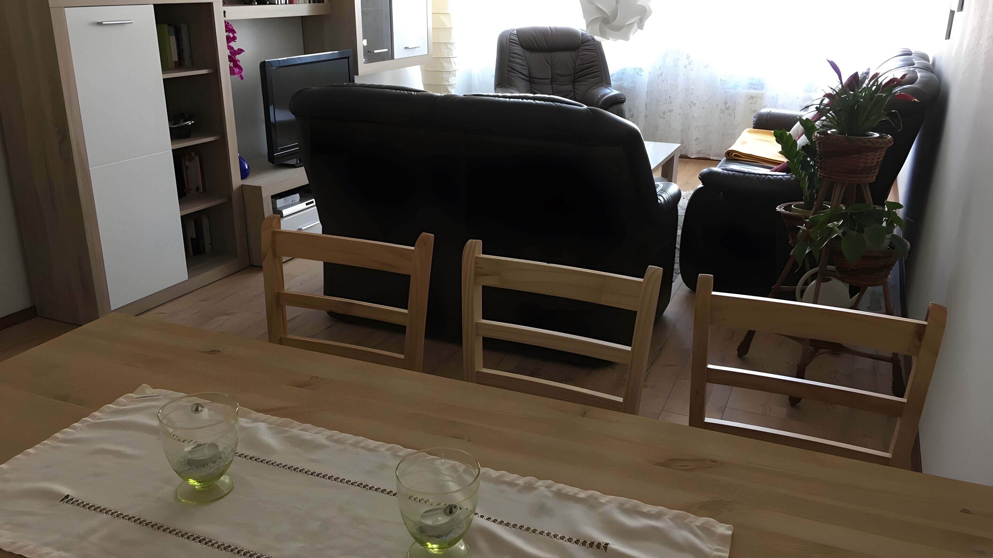 Een eethoek met een houten tafel, twee stoelen, een computer en een potplant.