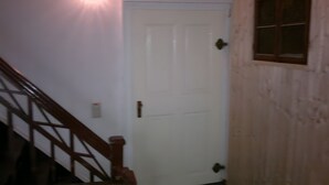 A white door with a brass handle, a wooden staircase with a handrail, and a window with a grid pattern. - Holiday Apartment for 2 Guests (63 m²) in Zittau (Zittau)