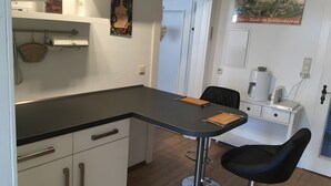 A kitchen with a black countertop, white cabinets, a coffee machine, and a wall-mounted sign. - Holiday Apartment for 2 Guests (63 m²) in Zittau (Zittau)