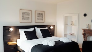 A modern bedroom with a black headboard, white bedding, and two framed artworks on the wall. - Hotel Château Palacio (Fauvillers)