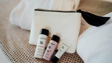 Une trousse de toilette blanche contenant trois produits : un flacon de produit de soin de la peau de la marque « ELLA BACHE », un tube de produit de soin de la peau de la marque « ELLA BACHE », et un petit flacon de produit de soin de la peau de la marque « ELLA BACHE ».