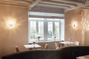 Un comedor con un ventanal grande, dos mesas y un sofá.