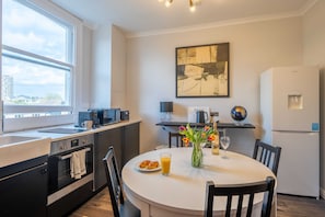 A modern kitchen with a dining area, a coffee machine, a globe, and a refrigerator.