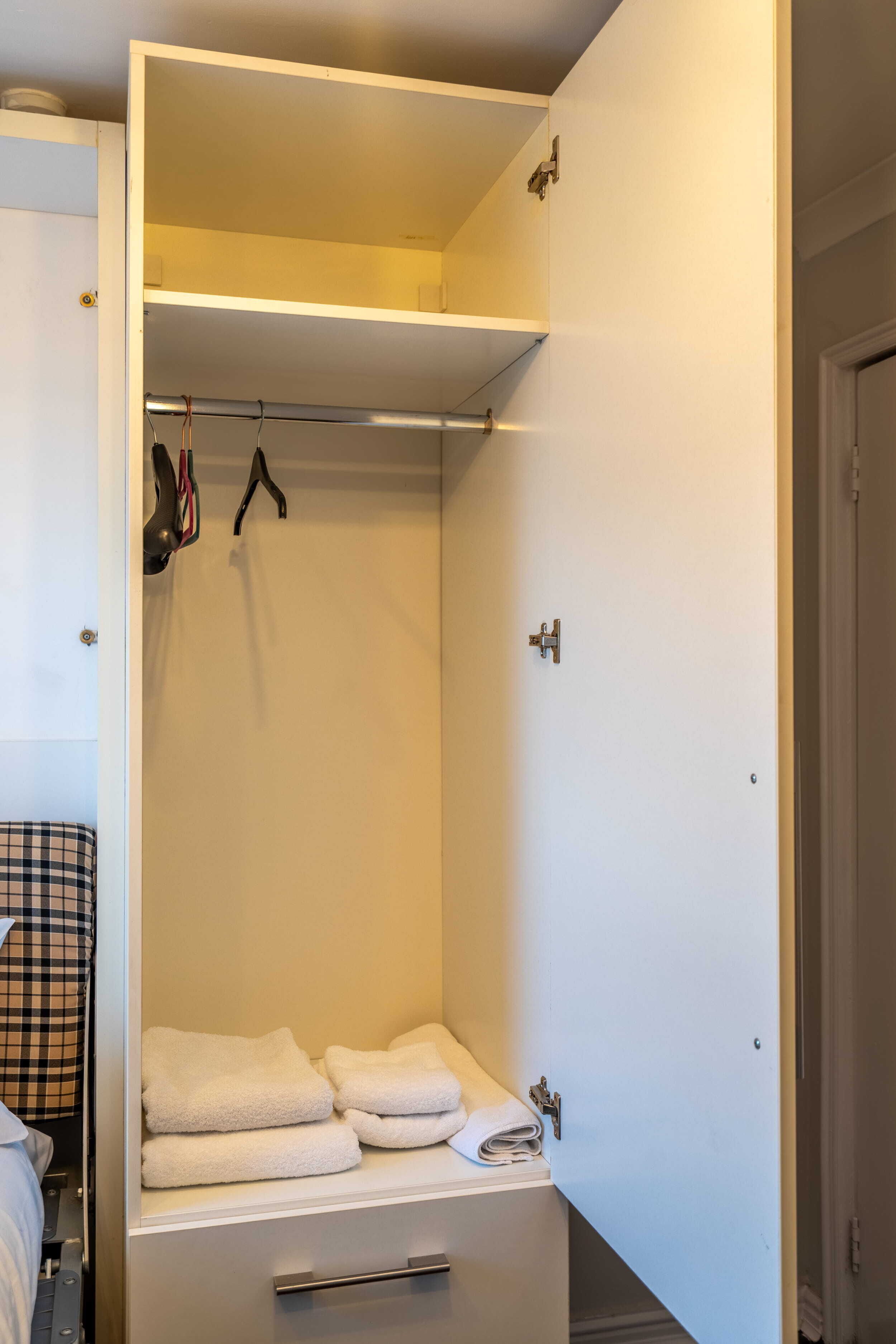Ein begehbarer Kleiderschrank mit Kleiderstange und einem Ablagefach für Handtücher.