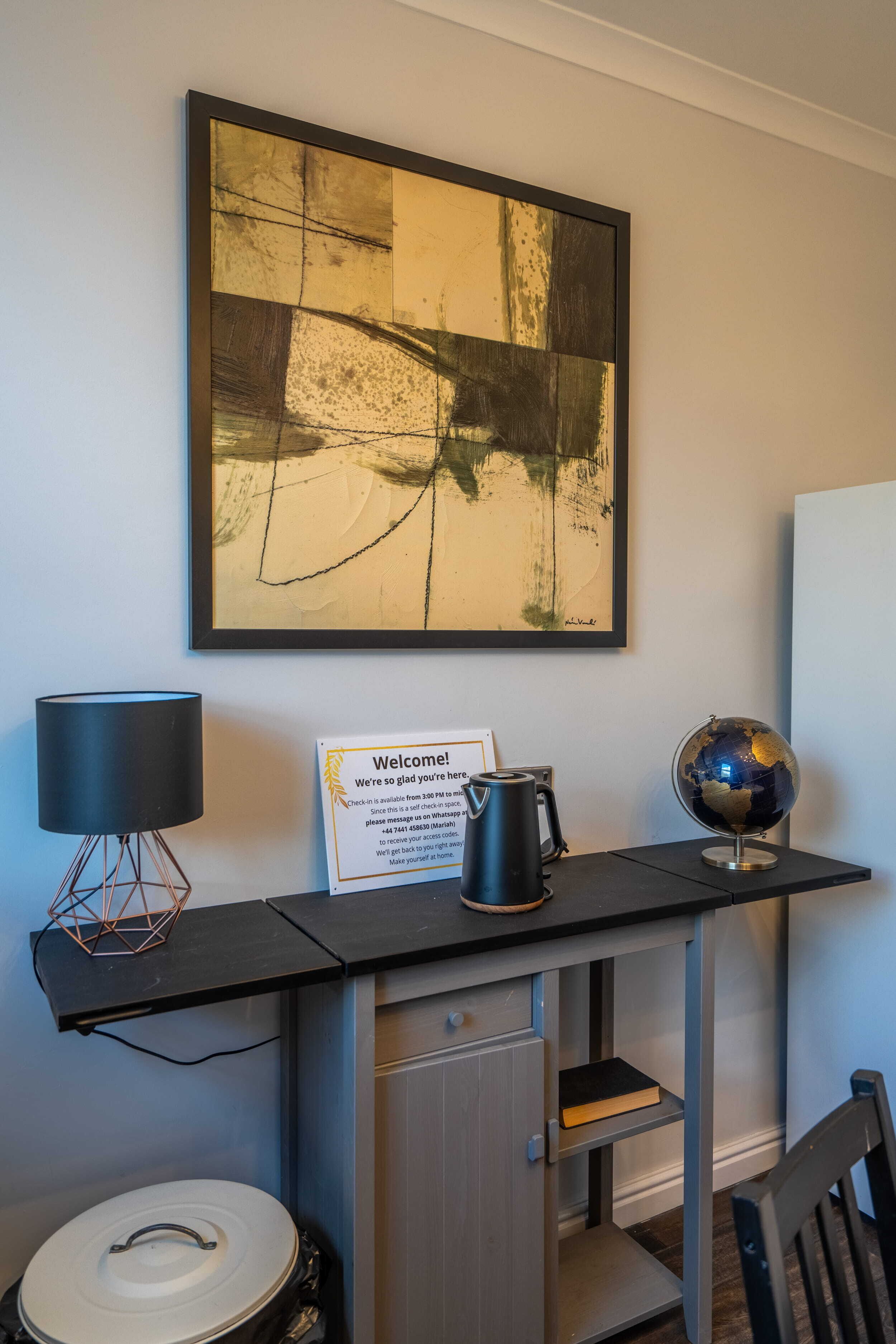 Un bureau avec un globe terrestre, une lampe, une machine à café et un panneau d’accueil.