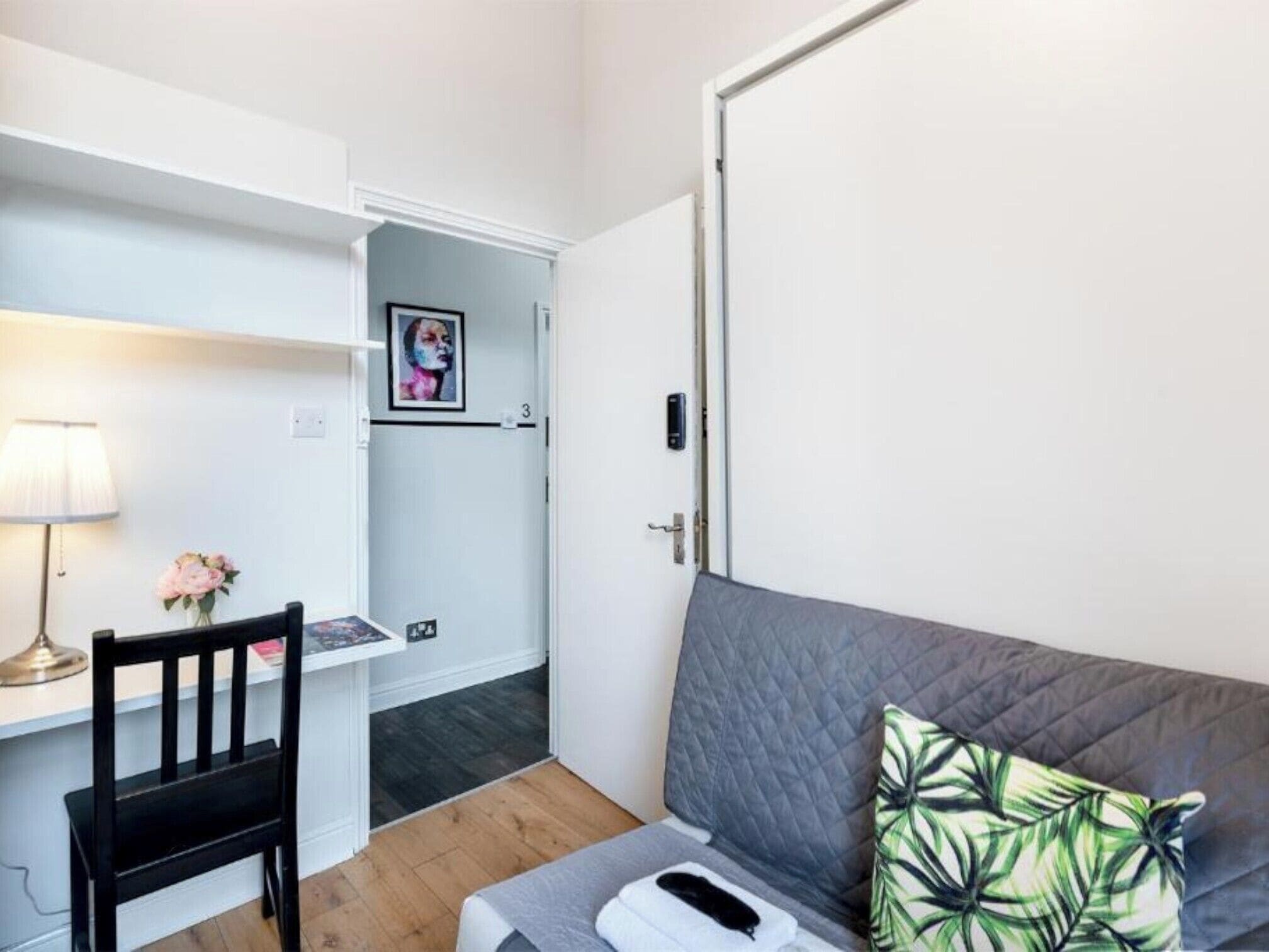 A room with a bed, a desk, a chair, a lamp, and a door.
