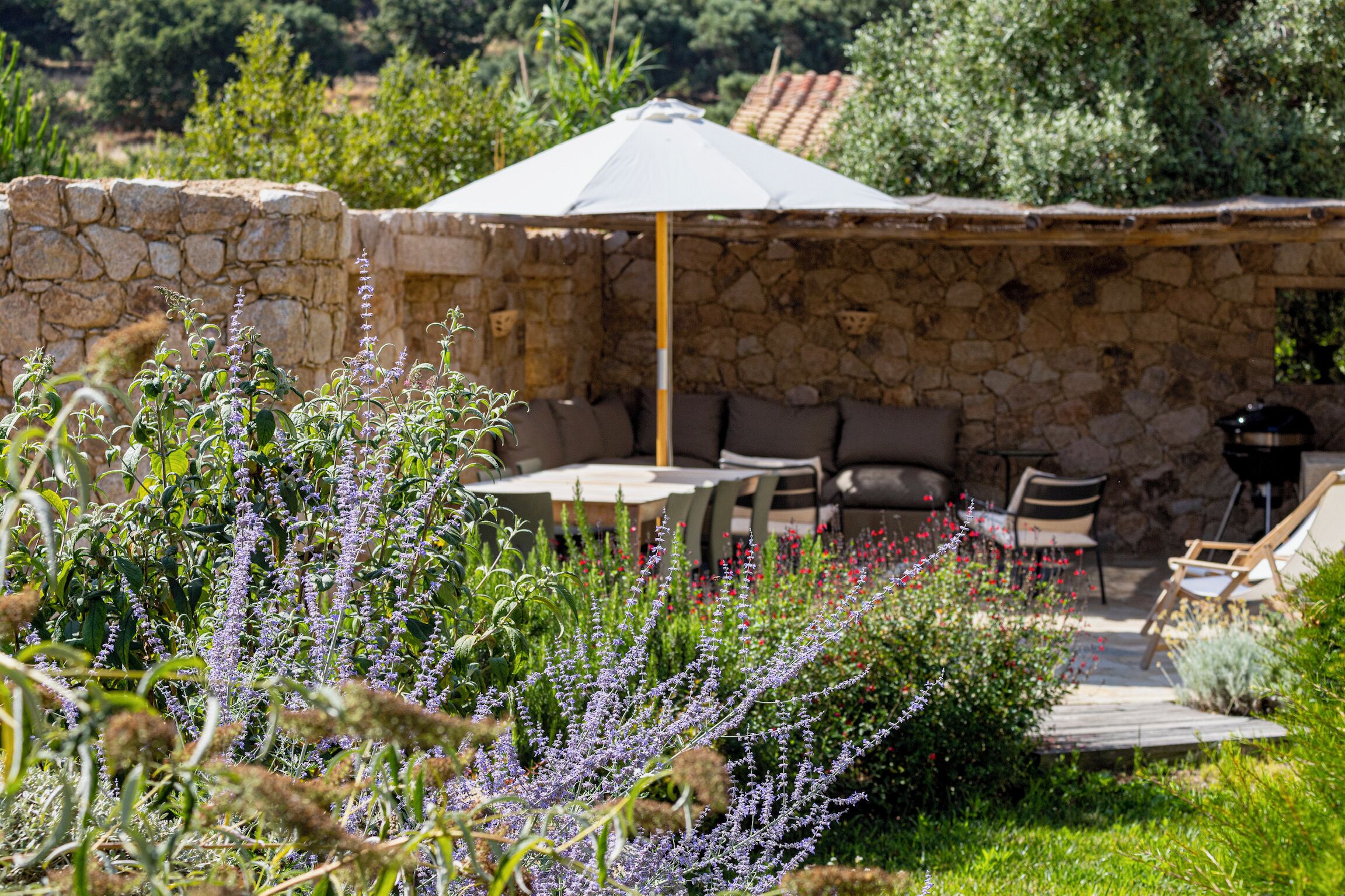 A stone wall, outdoor seating, and a table with an umbrella.