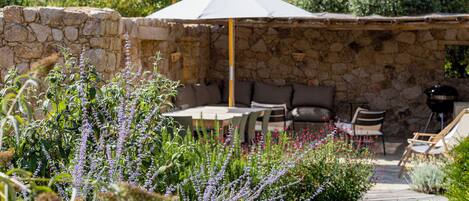 A stone wall, outdoor seating, and a table with an umbrella.