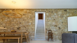A stone wall, a wooden bench, a dining table with a fruit bowl, a staircase, and a grey sofa. - Beautiful house on the edge of the charming village of Pigna (Pigna)