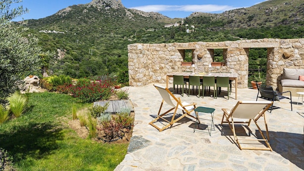A stone patio with outdoor furniture, a stone wall, and a view of a mountainous landscape. - Beautiful house on the edge of the charming village of Pigna (Pigna)