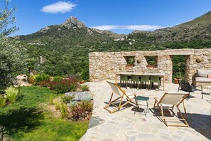A stone patio with outdoor furniture, a stone wall, and a view of a mountainous landscape. - Beautiful house on the edge of the charming village of Pigna (Pigna)