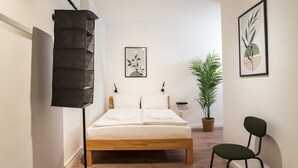 Et pænt opredt soveværelse med en træseng, en gulvlampe, en potteplante og to billeder i rammer på væggen.