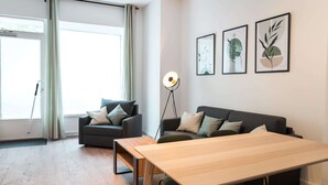 En moderne stue med sofa, spisebord og gulvlampe.