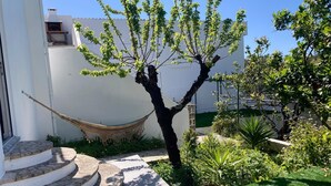 Un jardín con una hamaca, un árbol y una escalera.