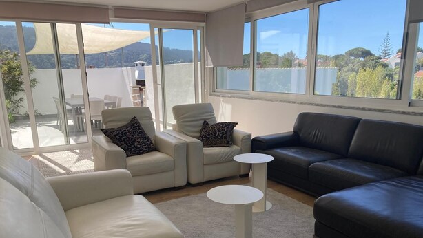Una sala de estar moderna con un sofá, dos sillones, una mesa de centro y vistas al exterior.