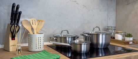 A kitchen with a wooden countertop, stainless steel pots, a knife block, and a green towel.