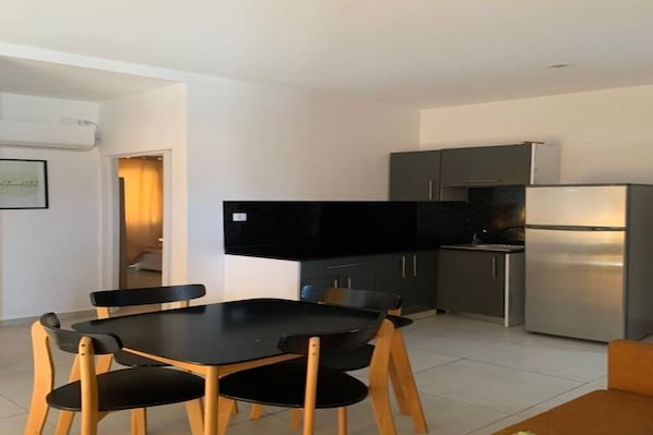 A modern kitchen with a dining table and chairs, a refrigerator, and cabinets.