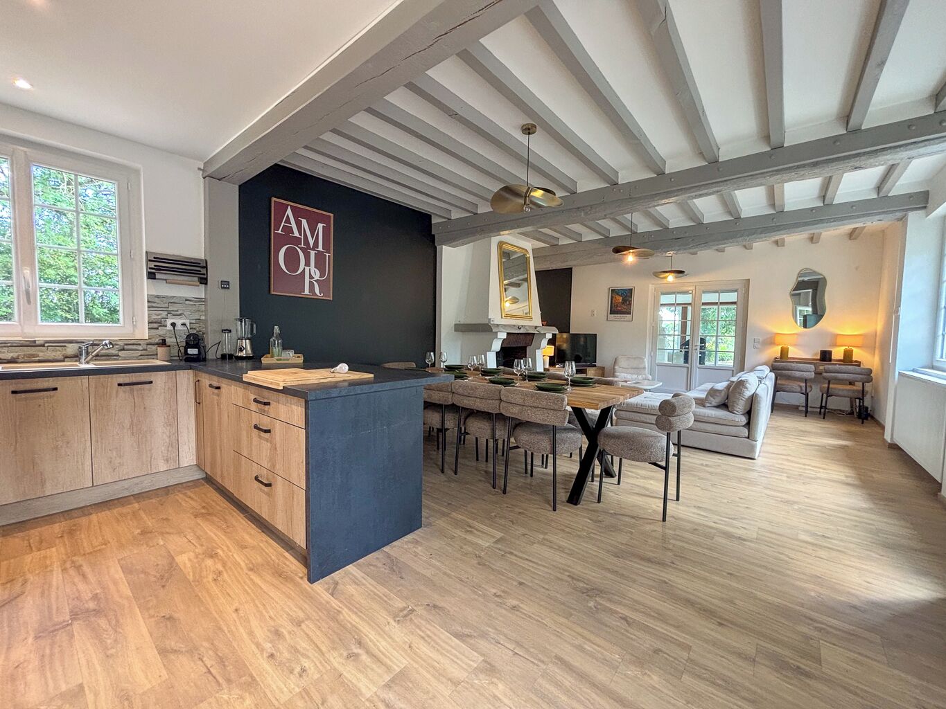 A modern kitchen with a central island, wooden cabinets, and a dining area with a sofa and chairs.