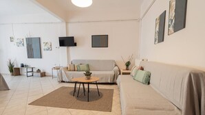Ein modernes Wohnzimmer mit einer Couch, einem Couchtisch und einem an der Wand befestigten Fernseher.