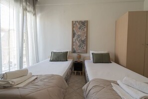 Ein Hotelzimmer mit zwei Betten, einem Nachttisch, einem Kleiderschrank und einem Fenster mit Vorhängen.