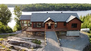 Une cabane avec une terrasse, un quai et une vue sur un lac entouré de forêt.