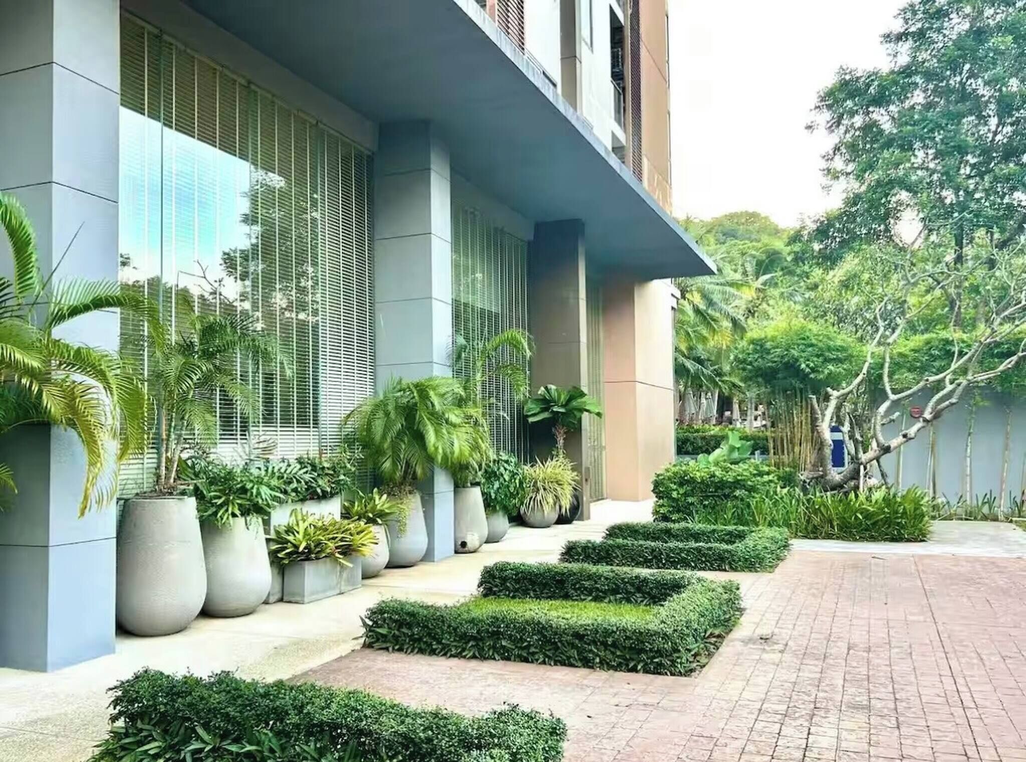 Un edificio moderno con ampie finestre, piante in vaso e un vialetto lastricato.