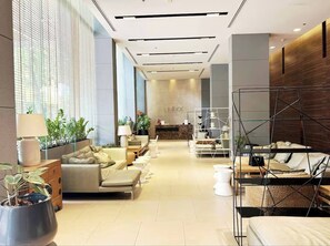 A modern hotel lobby with a sofa area, a reception desk, and a bed with a metal frame. - Pattaya Studio Walk to Beach Walking Street (Pattaya)