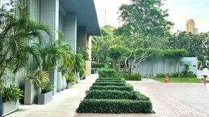 A modern building with a paved walkway, potted plants, and a neatly trimmed hedge. - Pattaya Studio Walk to Beach Walking Street (Pattaya)