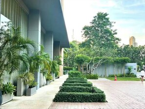 A modern building with a paved walkway, potted plants, and a neatly trimmed hedge. - Pattaya Studio Walk to Beach Walking Street (Pattaya)