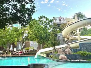 A pool with a water slide, lounge chairs, and a rocky landscape. - Pattaya Studio Walk to Beach Walking Street (Pattaya)