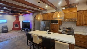 A modern kitchen with wooden cabinets, a central island, and pendant lighting. - The Big House Baja - 5BR Vacation Rental with Private Pool (San Felipe)