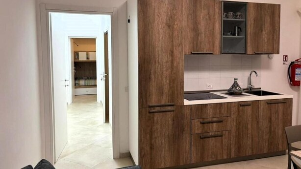 A modern kitchen with wooden cabinets, a sink, and a countertop. - Il Lentisco (Lecce)